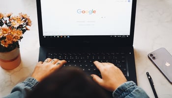 Fingers on keyboard with google on screen