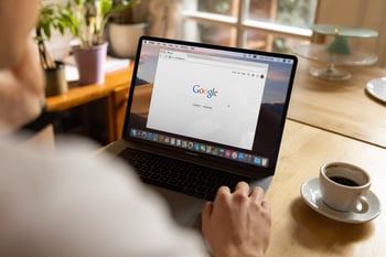 Hands on a laptop with google and coffee nearby