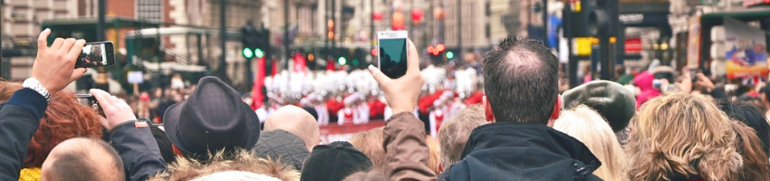 Women holding her phone capturing a parade