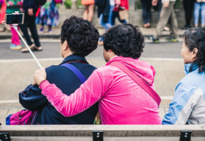 Three using a self stick to take a photo