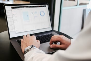 Laptop showing data with persons hands