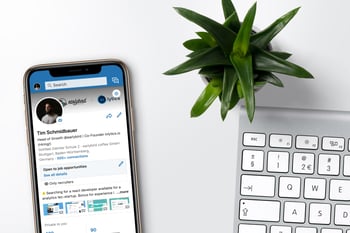 LinkedIn on phone on a desk with a plant