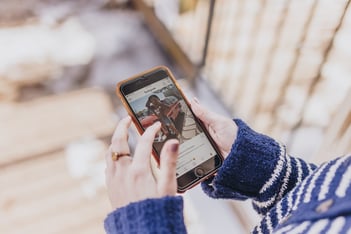 Hands shown through blue sweater holding iphone on Instagram