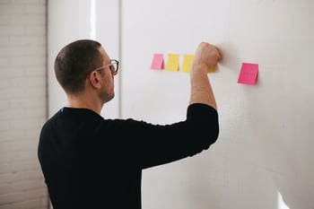 Person attaching postit notes to a whiteboard-1