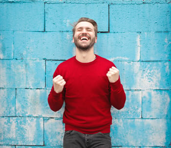 Man in front of blue brick wall smiling