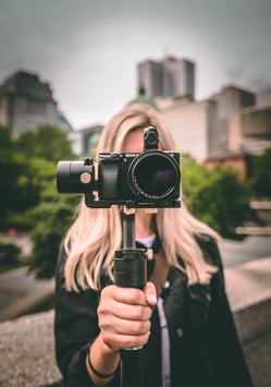 Woman holding a camera taking video in city